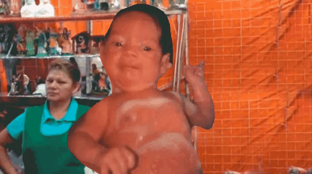 a woman in a green apron is standing in front of a baby