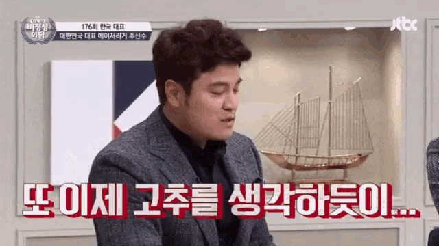 a man in a suit is sitting in front of a model boat and talking in a foreign language ..