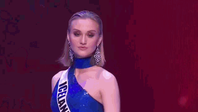a woman is standing on a stage wearing a blue dress .