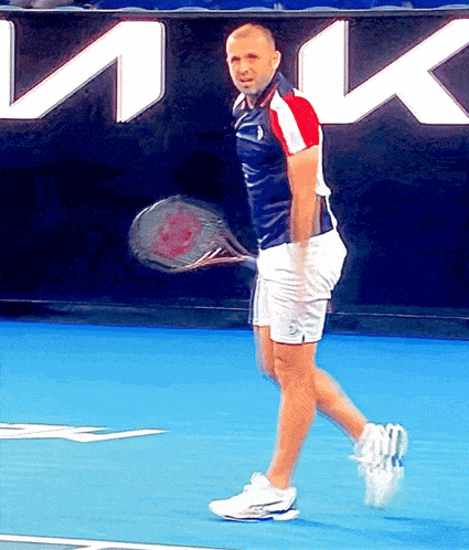 a man is holding a tennis racquet on a tennis court in front of a sign that says ink