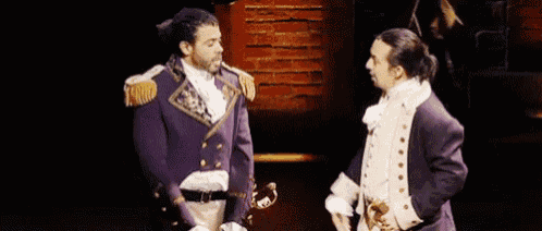 two men in military uniforms are standing next to each other on a stage and talking to each other .