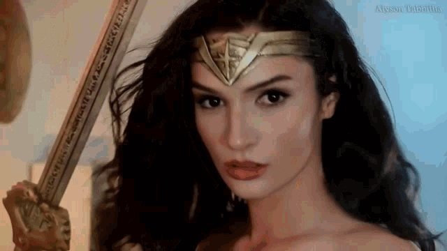 a woman in a wonder woman costume is holding a sword in her hand .