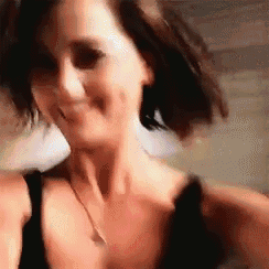 a woman in a black top and necklace is smiling .