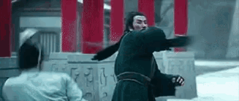 a man in a black robe is fighting another man in a black robe in front of a building .