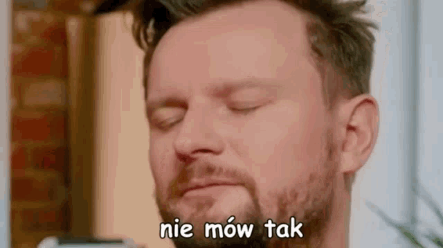 a man with a beard is making a funny face with his eyes closed and the words nie mow tak written above him .