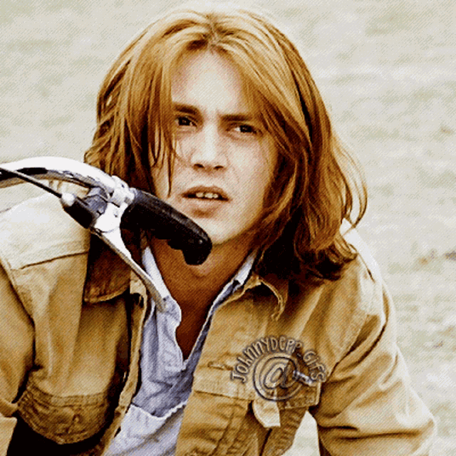 a man with long red hair is wearing a jacket that says tommydope