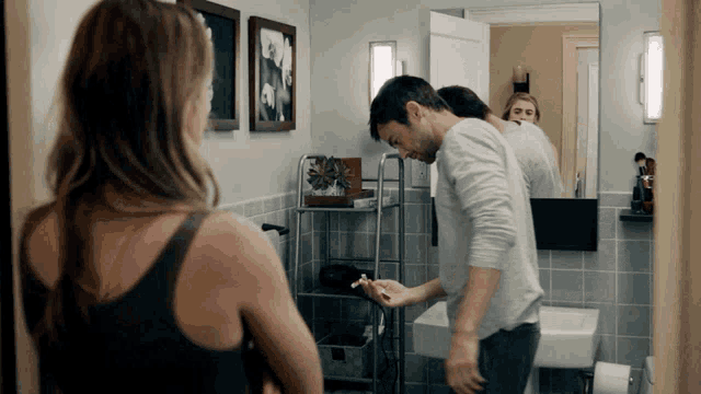 a man and a woman are in a bathroom looking at their reflection in the mirror