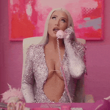 a woman in a very revealing dress talking on a pink phone