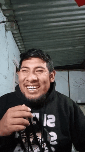 a man wearing a black sweatshirt with the word supreme on it is smiling
