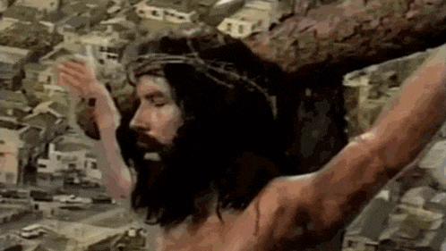 jesus wearing a crown of thorns is hanging on a cross .