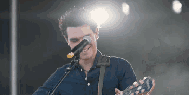 a man is singing into a microphone while playing a guitar