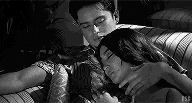 a man and a woman are laying on a couch and hugging each other .