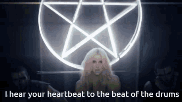 a woman stands in front of a pentagram with the words i hear your heartbeat to the beat of the drums