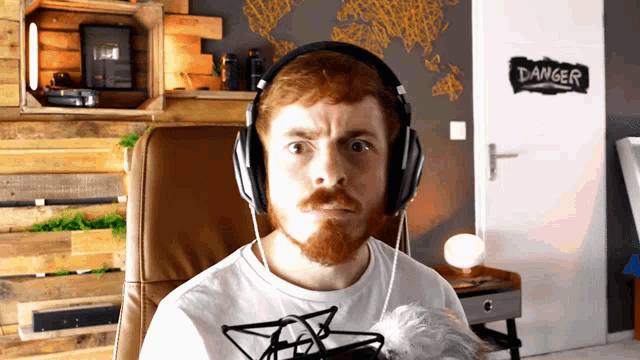 a man wearing headphones is sitting in front of a door that says danger