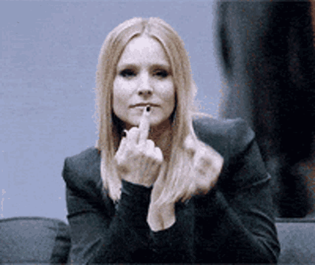 a woman in a black jacket is giving the middle finger to the camera