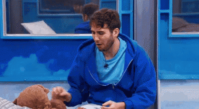 a man in a blue hoodie is holding a teddy bear .