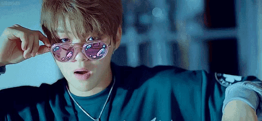 a young man wearing sunglasses and a necklace .