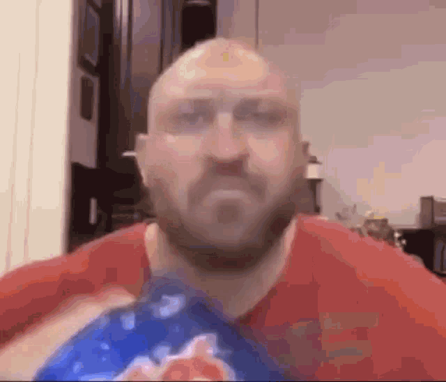 a bald man with a beard is holding a bag of chips in his hand .