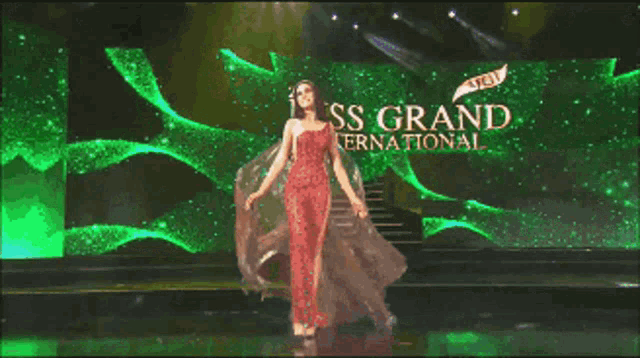 a woman in a red dress is standing in front of a sign that says miss grand international
