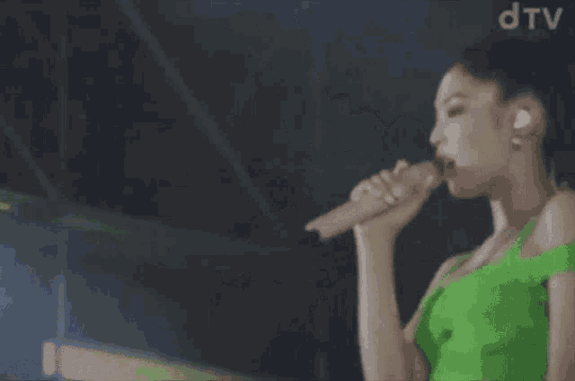a woman in a green dress singing into a microphone