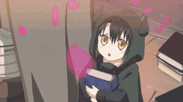 a little girl in a hooded jacket is holding a blue book