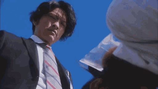 a man in a suit and tie looks down at another man