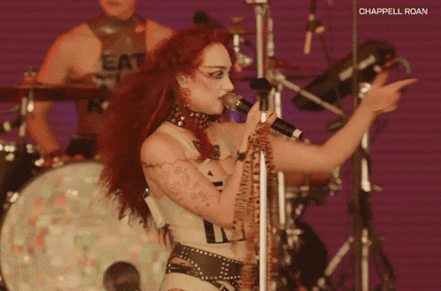 a woman with red hair singing into a microphone with the words chappelle roan written on the bottom