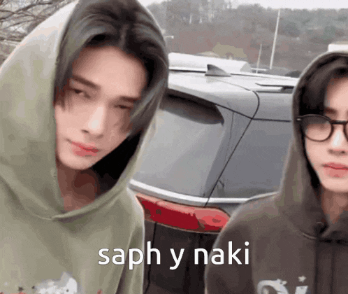 a man wearing a hoodie and glasses is standing next to another man wearing glasses .