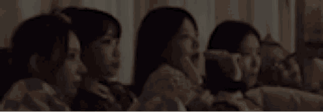 a group of women are sitting on a couch watching a movie together .