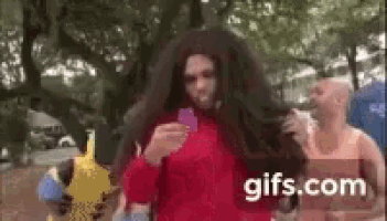 a man with a wig on his head is holding a card in his hand .