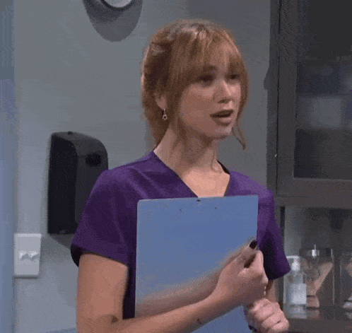 a woman in a purple scrub holds a clipboard