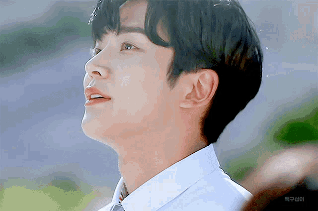 a close up of a young man 's face with a white shirt and tie looking up
