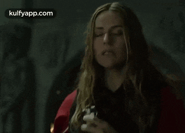 a woman with long blonde hair is standing in a dark room holding a gun .