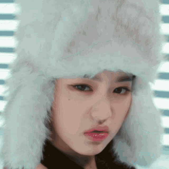 a woman wearing a fur hat is making a funny face