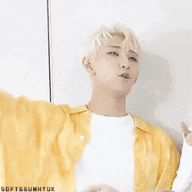 a young man with blonde hair is wearing a yellow shirt and white t-shirt