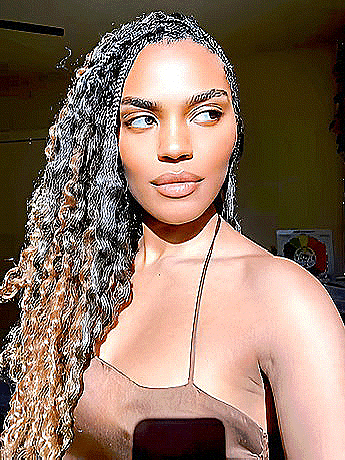a woman with braids in her hair is taking a selfie with her cell phone .