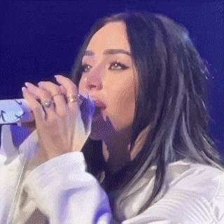a woman is singing into a microphone on stage .