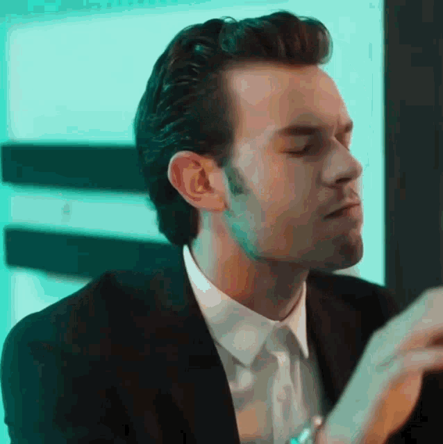 a man in a suit and tie is looking down at something .