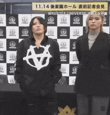 two women are standing in front of a wall that says universe