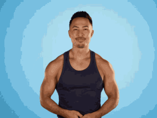 a man in a blue tank top is standing with his hands on his hips
