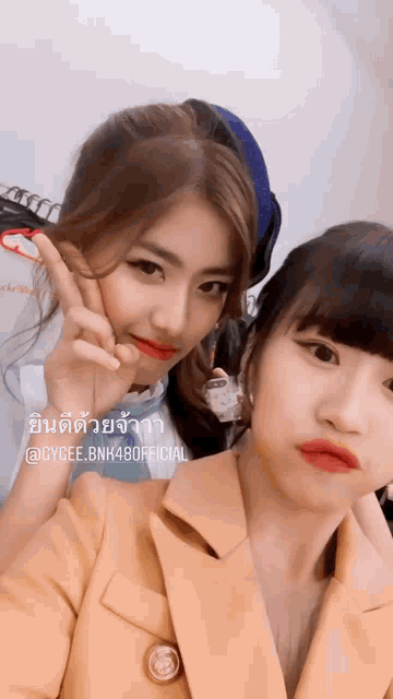 two girls are posing for a picture and one of them is wearing a jacket