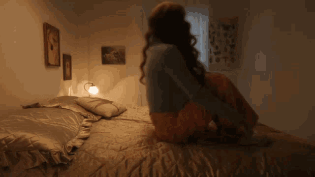 a woman sits on a bed in front of a sign that says ' abc '