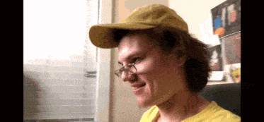 a man wearing glasses and a yellow hat is smiling