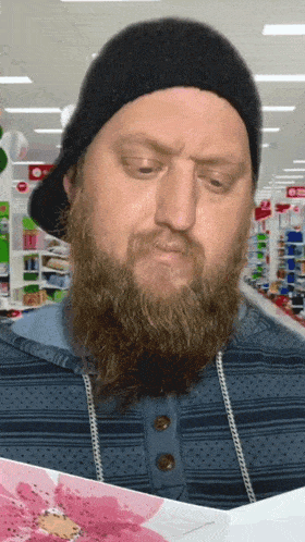 a man with a beard wearing a black hat is looking at a card