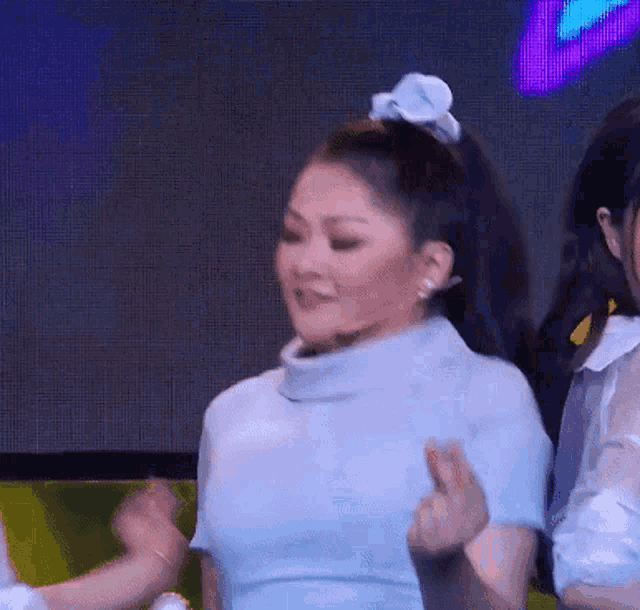 a woman in a blue sweater is dancing on stage