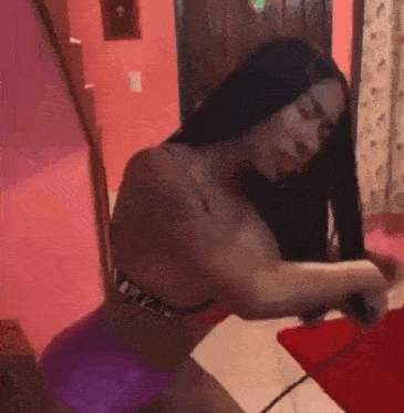 a woman is sitting on a bed in a pink room .