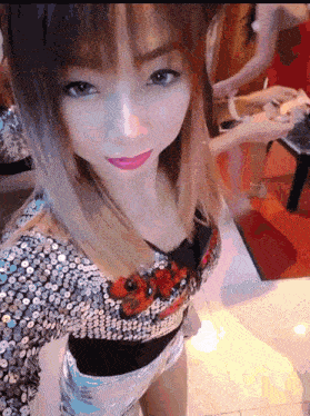 a woman wearing a sequined top and shorts looks at the camera