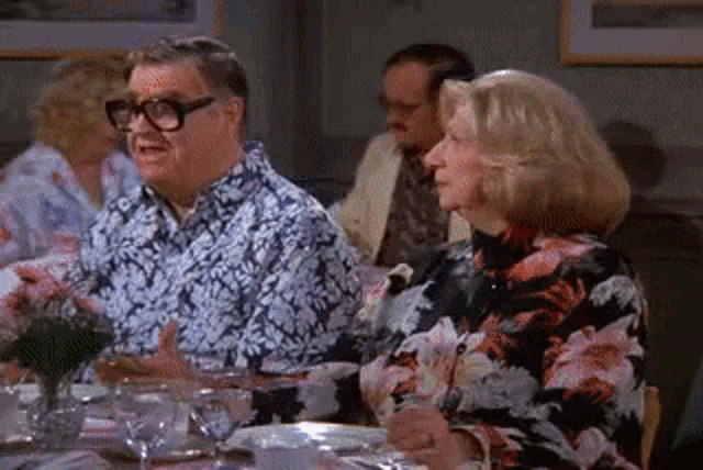 a man and a woman are sitting at a table with glasses and plates .