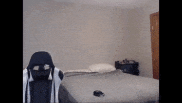 a man is standing next to a bed in a bedroom with a chair .