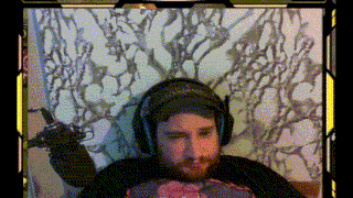 a man with a beard is wearing headphones and holding a microphone while sitting on a bed